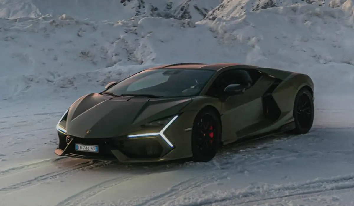 Lamborghini Revuelto оливкового цвета на заснеженной дороге на фоне гор, чёрные диски, красные суппорты