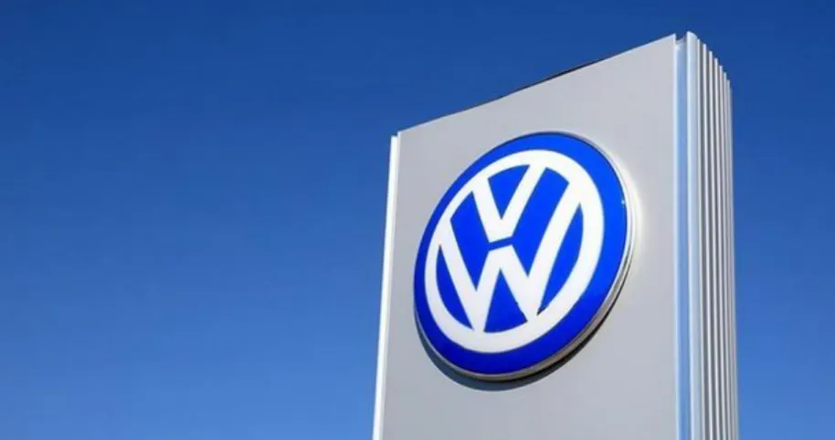 Серебристая стела с синим круглым логотипом Volkswagen на фоне безоблачного синего неба